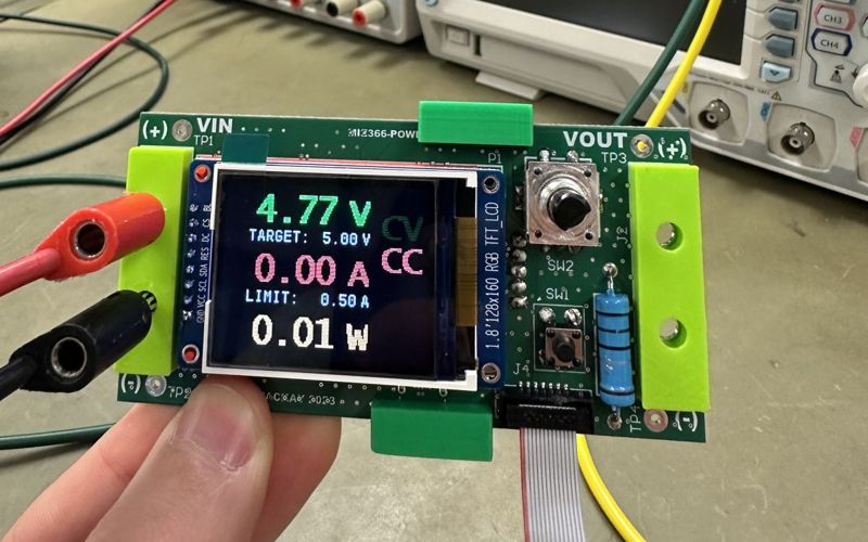 The power supply board on a lab bench, its screen reading 4.77 V